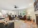 Comfortable living room with brown sofa, ceiling fan, fireplace, and large windows overlooking trees at 327 Whitestone Rd, Charlotte, NC 28270