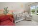 Bright Bedroom with desert theme mural, white crib, red chair, and neutral rocker, with natural light from the window at 416 Linestowe Dr, Belmont, NC 28012