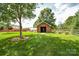 Lush backyard with shed, greenhouse, and mature trees, offering a serene outdoor space at 4320 Atkinson Way, Monroe, NC 28110