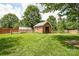 Well-maintained backyard featuring a storage shed, a greenhouse, a fence, and mature trees at 4320 Atkinson Way, Monroe, NC 28110