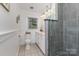 Modern bathroom featuring glass enclosed shower with gray tile, white cabinets, and a large bright window at 441 Crestside Se Dr, Concord, NC 28025