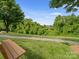Scenic view of lush green space with a pond, walking path, mature trees, and a bench for relaxation at 4607 Silk Tree Ln, Rock Hill, SC 29732