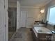 Bright bathroom features a large soaking tub, glass shower, and tiled floor at 5000 Britannia Blvd, Waxhaw, NC 28173