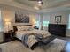 Inviting main bedroom suite featuring a tray ceiling, soft carpet, a king bed, and ensuite bathroom at 5000 Britannia Blvd, Waxhaw, NC 28173