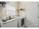 Laundry room featuring modern washer and dryer units; shelving for storage and convenient door access at 5111 Elementary View Dr, Charlotte, NC 28269