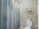 Bathroom featuring a shower with patterned curtain, toilet, and mounted metal shelving for storage at 6044 Heath Valley Rd, Charlotte, NC 28210