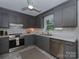 Updated kitchen featuring gray cabinetry, stainless steel appliances, white subway tile backsplash, and marble countertops at 713 Springfield Nw Dr, Concord, NC 28027
