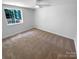 An empty bedroom features neutral carpeting and a window overlooking the backyard at 7134 Rollingridge Dr, Charlotte, NC 28211