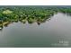 Aerial view of a luxurious lake house surrounded by mature trees with dock access at 7945 Placid Ct, Denver, NC 28037