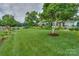 Well-manicured front yard featuring lush green grass, mature trees, and meticulously maintained landscaping at 7945 Placid Ct, Denver, NC 28037