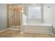 Bright bathroom showcasing a bathtub with tile and shower with glass door, and a large window at 8115 Kelburn Ln, Charlotte, NC 28273