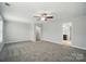 A bedroom with an adjacent bathroom and walk-in closet, ceiling fan and plush carpet at 8115 Kelburn Ln, Charlotte, NC 28273