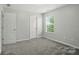 Bedroom featuring two doors and a window, with light-grey walls and carpet at 8115 Kelburn Ln, Charlotte, NC 28273