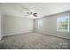 A serene bedroom with a ceiling fan and soft carpet, bathed in natural light from a large window at 8115 Kelburn Ln, Charlotte, NC 28273
