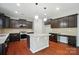 Modern kitchen featuring dark cabinets, granite countertops, a center island, and hardwood floors at 8115 Kelburn Ln, Charlotte, NC 28273