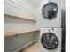 Efficient laundry area with stacked washer/dryer and shelving at 8115 Kelburn Ln, Charlotte, NC 28273