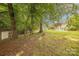 Serene backyard featuring mature trees, green grass, and a storage shed, creating a private outdoor space at 901 Clearbrook Rd, Matthews, NC 28105