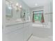 Bathroom with white double vanity, tub, and mirrors with sconces; a bright and elegant space at 9622 Penshurst Trce, Charlotte, NC 28210