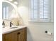 Charming powder room featuring a decorative sink, custom vanity, and window with shutters at 9622 Penshurst Trce, Charlotte, NC 28210
