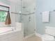 Elegant bathroom featuring a glass-enclosed shower, soaking tub, and neutral tile at 9622 Penshurst Trce, Charlotte, NC 28210