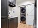 Modern laundry room with gray cabinets, a sink, and a stacked washer and dryer set at 9622 Penshurst Trce, Charlotte, NC 28210