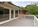 A covered back deck of a brick home features gray wooden floors and white railings with french doors to the interior at 10637 Highway 52 Hwy, Rockwell, NC 28138