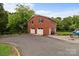 A brick two story garage has two white garage doors, black shutters, a basketball net and a paved driveway at 10637 Highway 52 Hwy, Rockwell, NC 28138