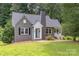 Quaint gray brick home featuring a side porch, teal door, and lush green lawn at 1106 S South St, Gastonia, NC 28052