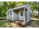 Exterior view of a backyard shed featuring a small porch, multiple windows, and neutral siding at 113 W 5Th Ave, Gastonia, NC 28052