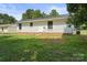 Backyard view of this home's exterior with mature trees and partial brick foundation at 1218 Milan Rd, Charlotte, NC 28216
