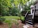 Backyard features deck with stairs, lush lawn, and wooded surroundings at 1423 Piper Ct, Concord, NC 28025