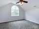 Empty bedroom with vaulted ceiling, neutral carpet, large window, and overhead fan at 1423 Piper Ct, Concord, NC 28025