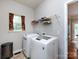 Functional laundry area with side by side washer and dryer, storage rack, and window at 1423 Piper Ct, Concord, NC 28025