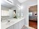 Bright bathroom with dual sinks, large mirror, white cabinets, and view to the bedroom at 1423 Piper Ct, Concord, NC 28025