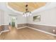 Bright dining room featuring modern chandelier, wood-look ceiling, and wainscotting at 18522 Victoria Bay Dr, Cornelius, NC 28031