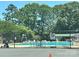 Community pool with lounge chairs and umbrellas surrounded by a tall metal fence at 214 Tenth St, Cramerton, NC 28032