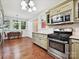 View of the eat-in kitchen with sage green cabinets, stainless appliances, hardwood floors, and bright lighting at 214 Tenth St, Cramerton, NC 28032