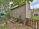 Storage shed in the backyard with steps leading up to the double doors and partial fencing at 214 Tenth St, Cramerton, NC 28032