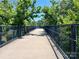 Community walking bridge lined with black metal railings and surrounded by green trees at 214 Tenth St, Cramerton, NC 28032