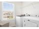 Bright laundry room with a large window, white washer and dryer, and wire shelving at 3038 Burnello Ct, Iron Station, NC 28080
