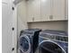 Well-lit laundry room featuring modern washer and dryer with upper cabinets at 318 N Dotger Ave, Charlotte, NC 28204