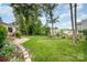 Spacious backyard featuring lush green grass, mature trees, and a charming landscape design at 3810 Yorkford Dr, Charlotte, NC 28269