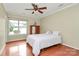 Comfortable bedroom features a ceiling fan, hardwood floors, and a large window for natural light at 4263 Melrose Club Dr, Matthews, NC 28105