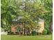 View of a brick two-story home with mature trees, a large lawn, and manicured landscaping at 4808 Cobble Glen Way, Charlotte, NC 28269