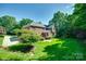 Large backyard featuring beautiful greenery surrounding a brick home with a manicured lawn at 5008 Woodview Ln, Weddington, NC 28104