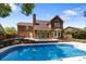 Backyard with a pool, brick patio, arched windows, and lush landscaping, perfect for entertaining at 7213 Baniff Cir, Charlotte, NC 28277