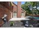 Exterior side view of a brick home featuring a fenced pool, patio, and garden with dark mulch at 7213 Baniff Cir, Charlotte, NC 28277