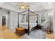 Bright bedroom featuring a four-poster bed, hardwood floors, and a decorative ceiling fan at 9637 Brookmere Ln, Charlotte, NC 28214