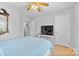 A well-lit bedroom with light hardwood floors, a television on a stylish desk, and a comfortable bed at 9637 Brookmere Ln, Charlotte, NC 28214