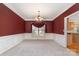 Formal dining room features a modern chandelier, red accent wall, and access to an adjacent room with kitchen features at 1002 Hollyhedge Ln, Indian Trail, NC 28079
